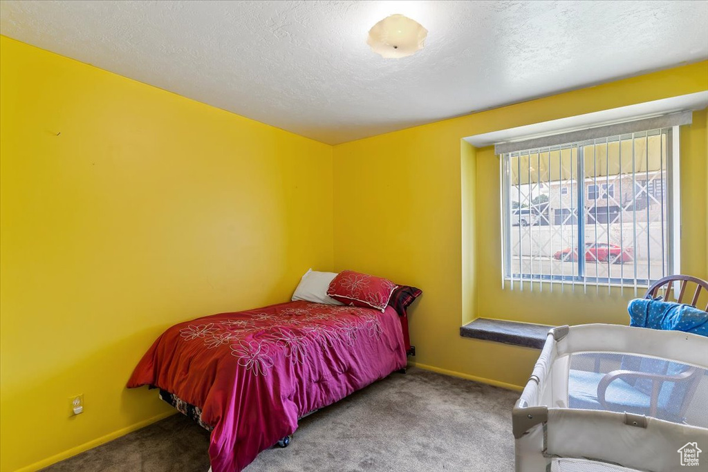Carpeted bedroom with a textured ceiling and baseboards