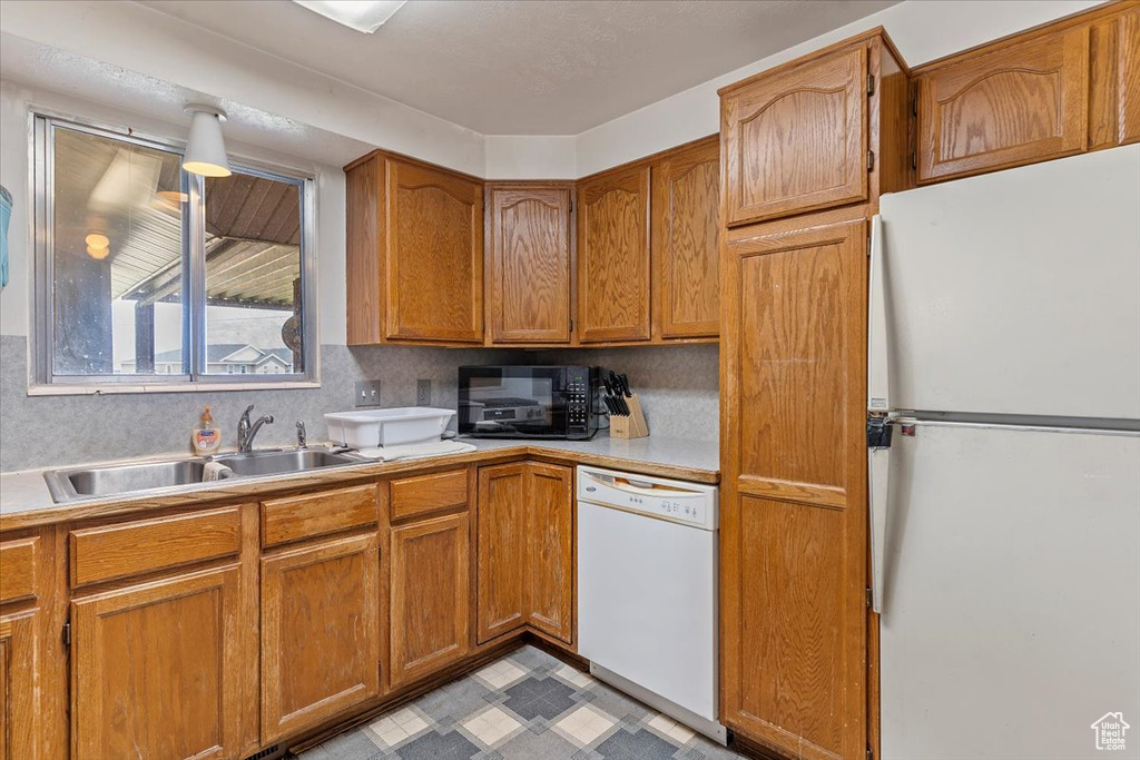 Kitchen with white appliances, light countertops, brown cabinetry, and light floors