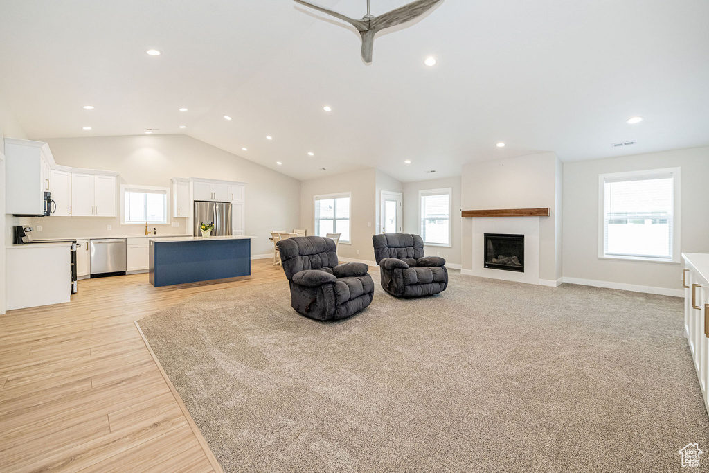 Living area featuring a fireplace, lofted ceiling, recessed lighting, a ceiling fan, and light wood-style floors