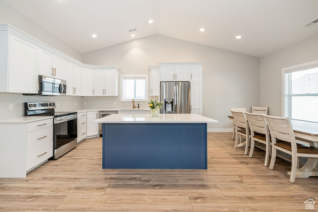 Kitchen featuring appliances with stainless steel finishes, a kitchen island, light countertops, recessed lighting, and white cabinetry
