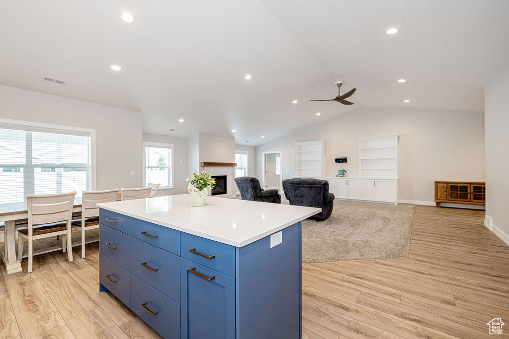 Kitchen with a kitchen island, light wood-style flooring, blue cabinets, ceiling fan, and lofted ceiling