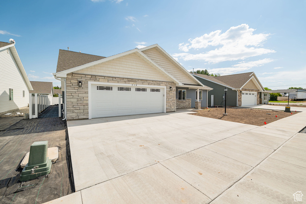 View of front of house with stone siding and driveway