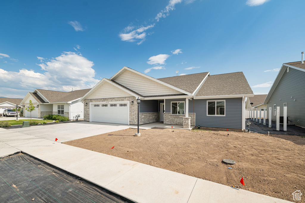 Single story home with a garage, driveway, and stone siding