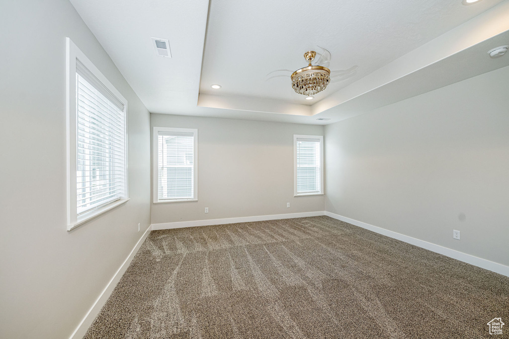 Empty room featuring carpet floors, recessed lighting, and a raised ceiling