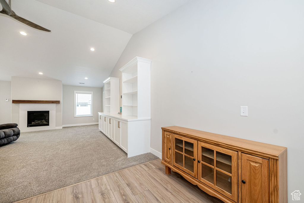 Living room with vaulted ceiling, recessed lighting, a fireplace, light wood-style flooring, and light colored carpet