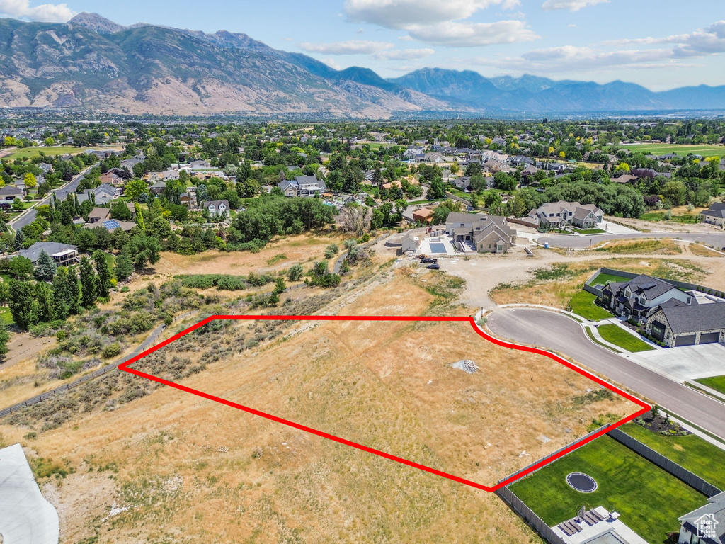 Aerial view of residential area with property parcel outlined and mountains