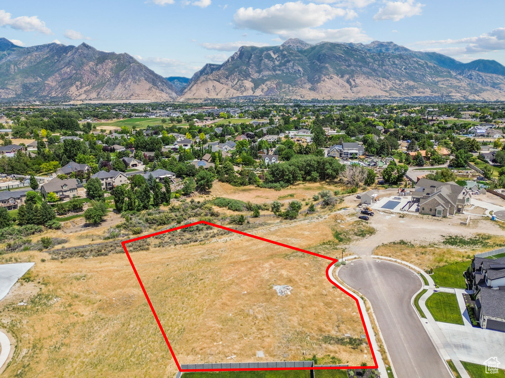 Aerial view of residential area featuring property boundaries highlighted and a mountainous background