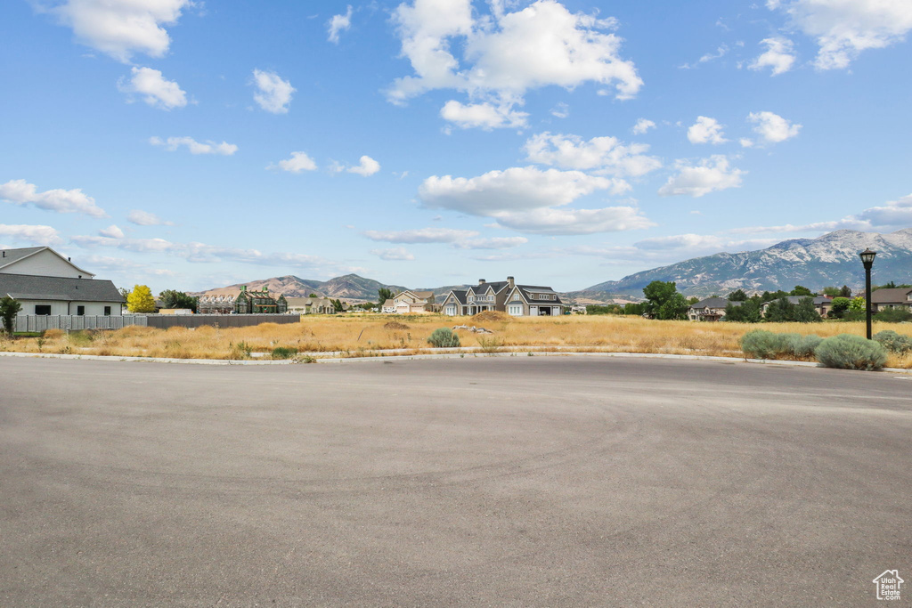 View of asphalt road with curbs, a mountain view, and street lighting