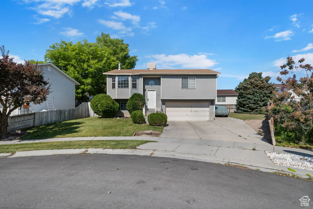 Bi-level home featuring an attached garage, driveway, and a chimney