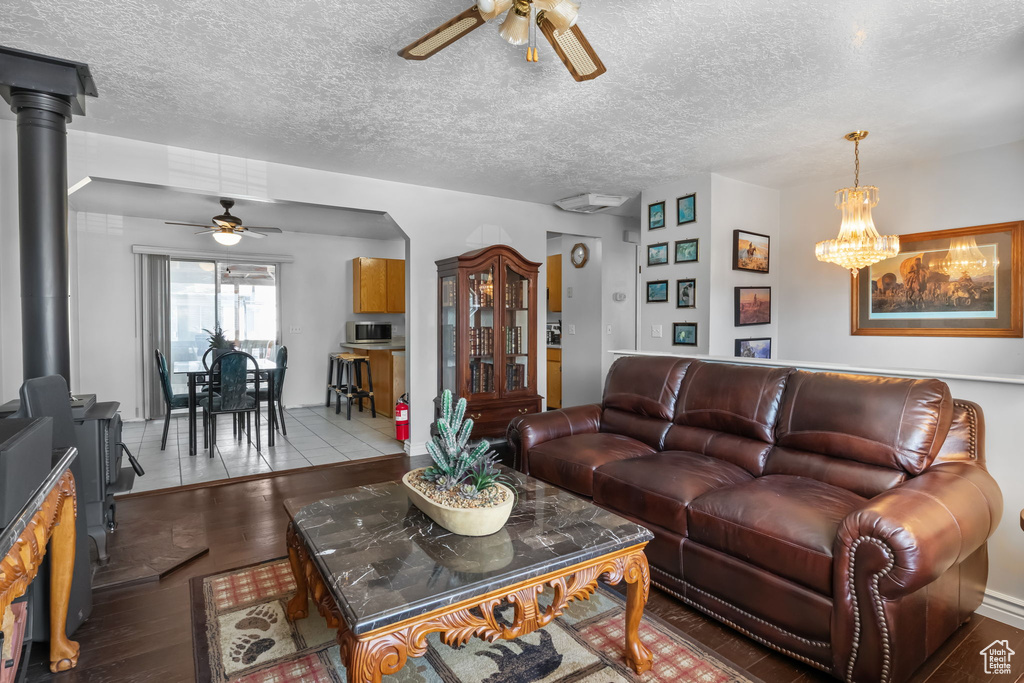 Living room featuring a ceiling fan, wood finished floors, a wood stove, and a textured ceiling