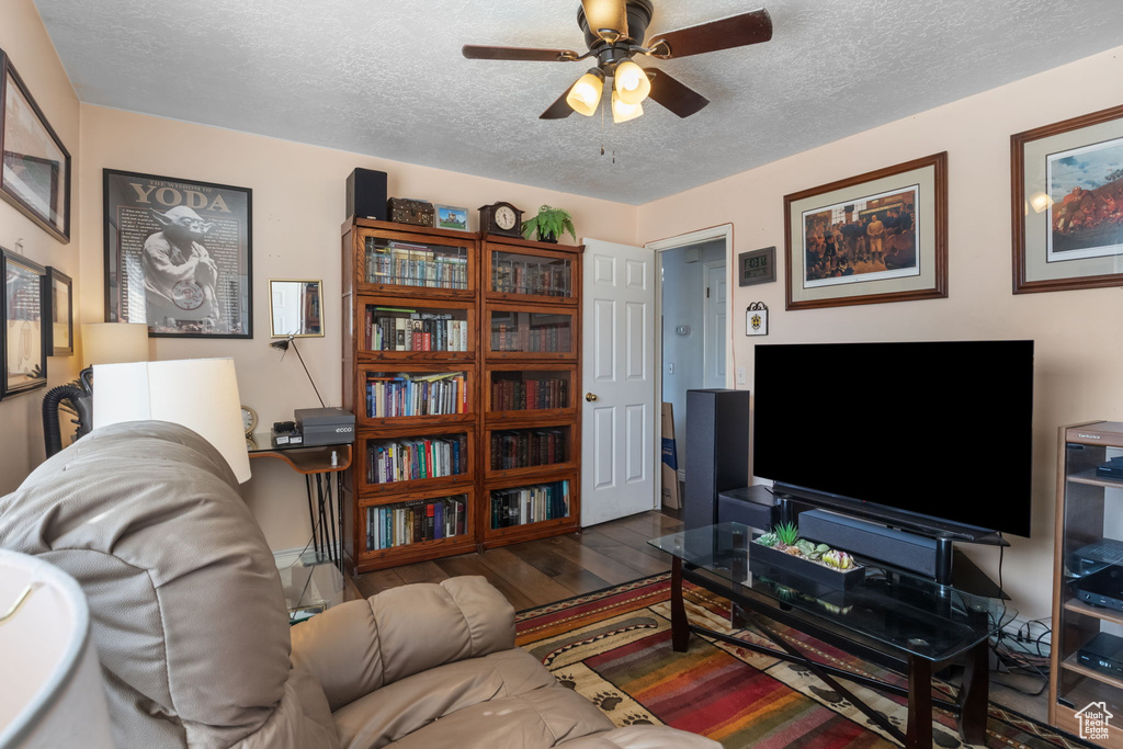 Living room with a textured ceiling, wood finished floors, and a ceiling fan