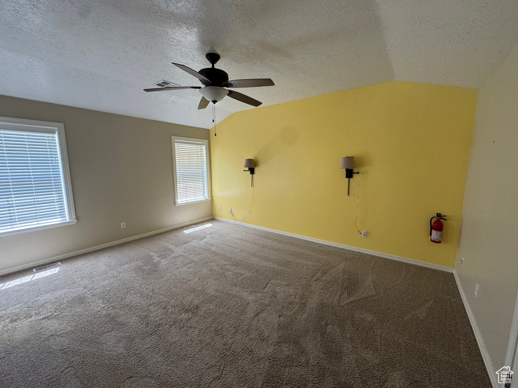 Unfurnished room with a textured ceiling, carpet flooring, a ceiling fan, and lofted ceiling