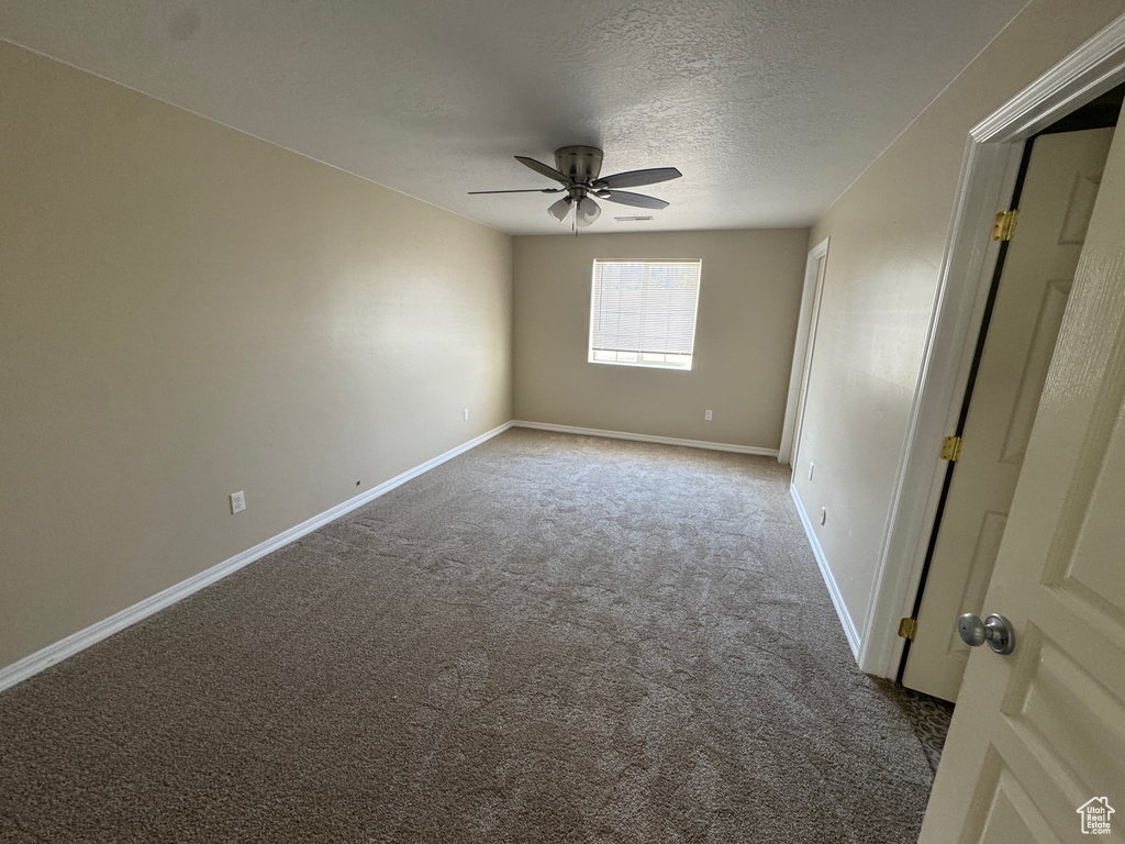 Carpeted spare room with ceiling fan and a textured ceiling