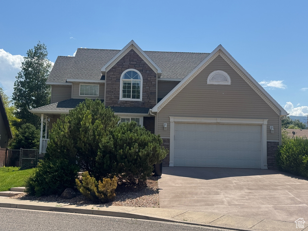View of front facade featuring stone siding, driveway, and an attached garage