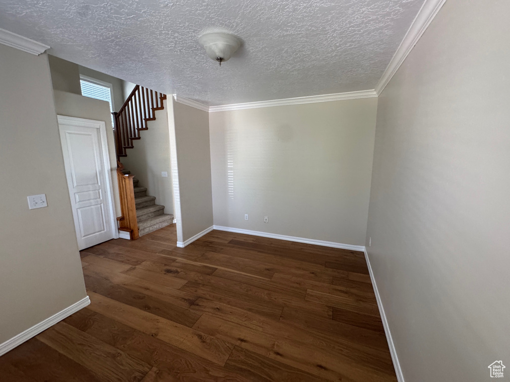 Unfurnished room with wood finished floors, stairway, a textured ceiling, and crown molding