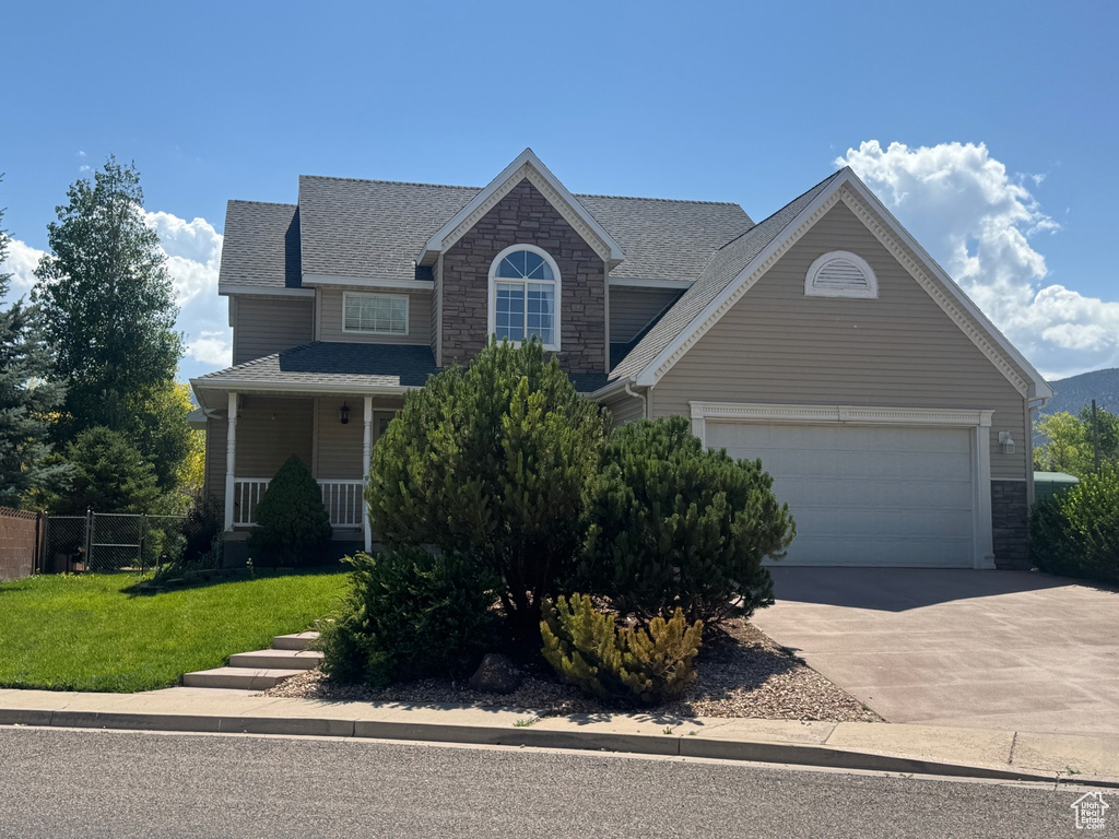Traditional home featuring stone siding, concrete driveway, a garage, and a porch