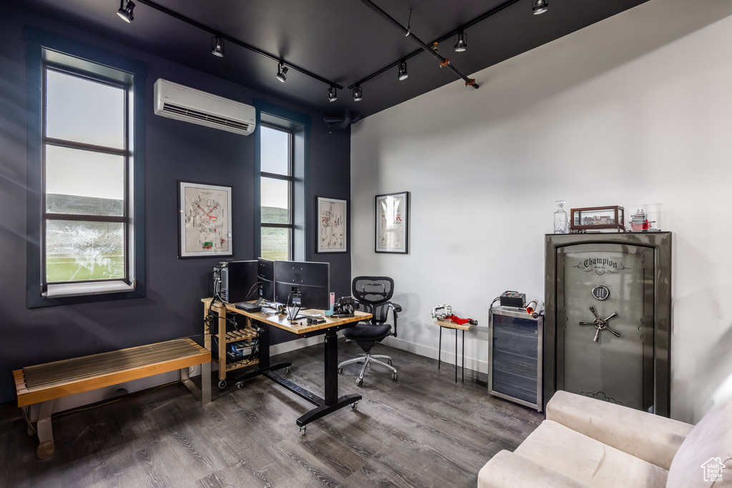 Office space with an AC wall unit, wood finished floors, rail lighting, and beverage cooler