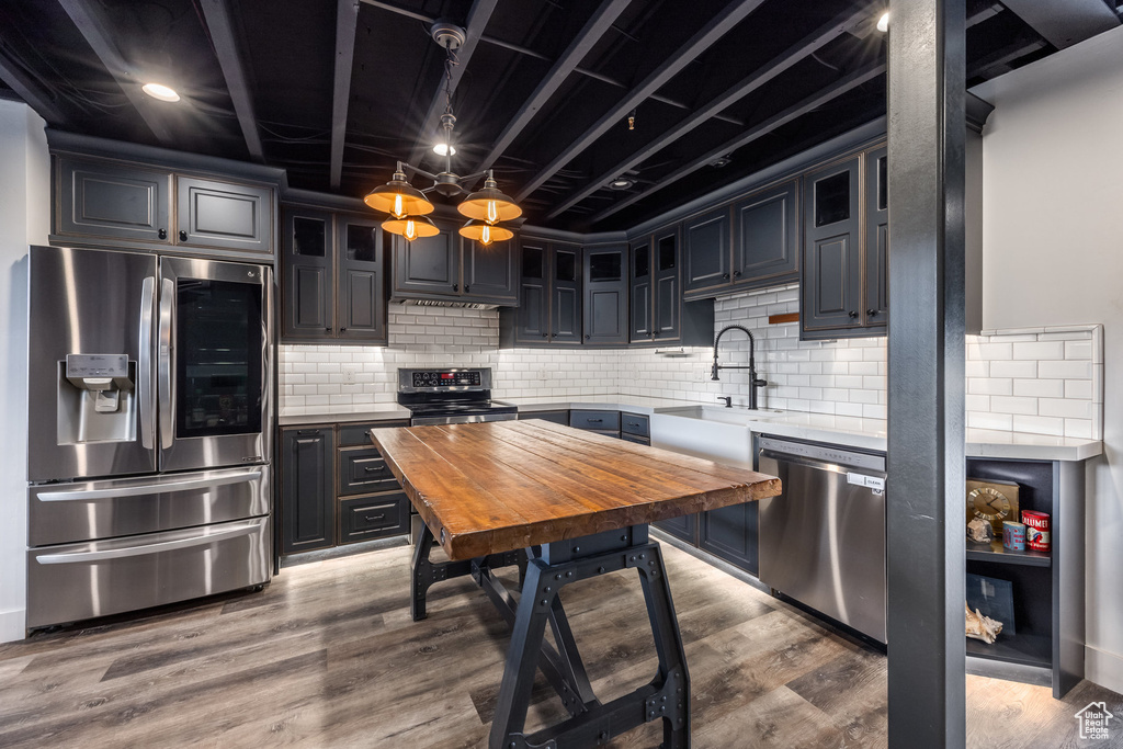 Kitchen with stainless steel appliances, glass insert cabinets, tasteful backsplash, and wood finished floors