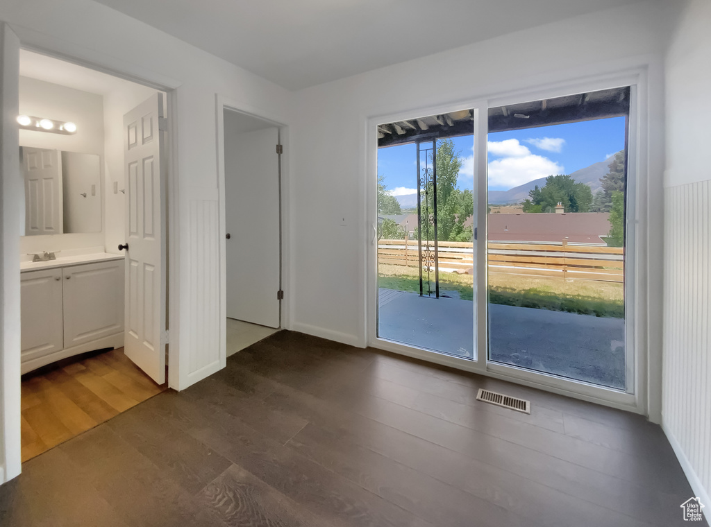 Unfurnished bedroom featuring access to exterior, dark wood finished floors, a mountain view, and ensuite bathroom