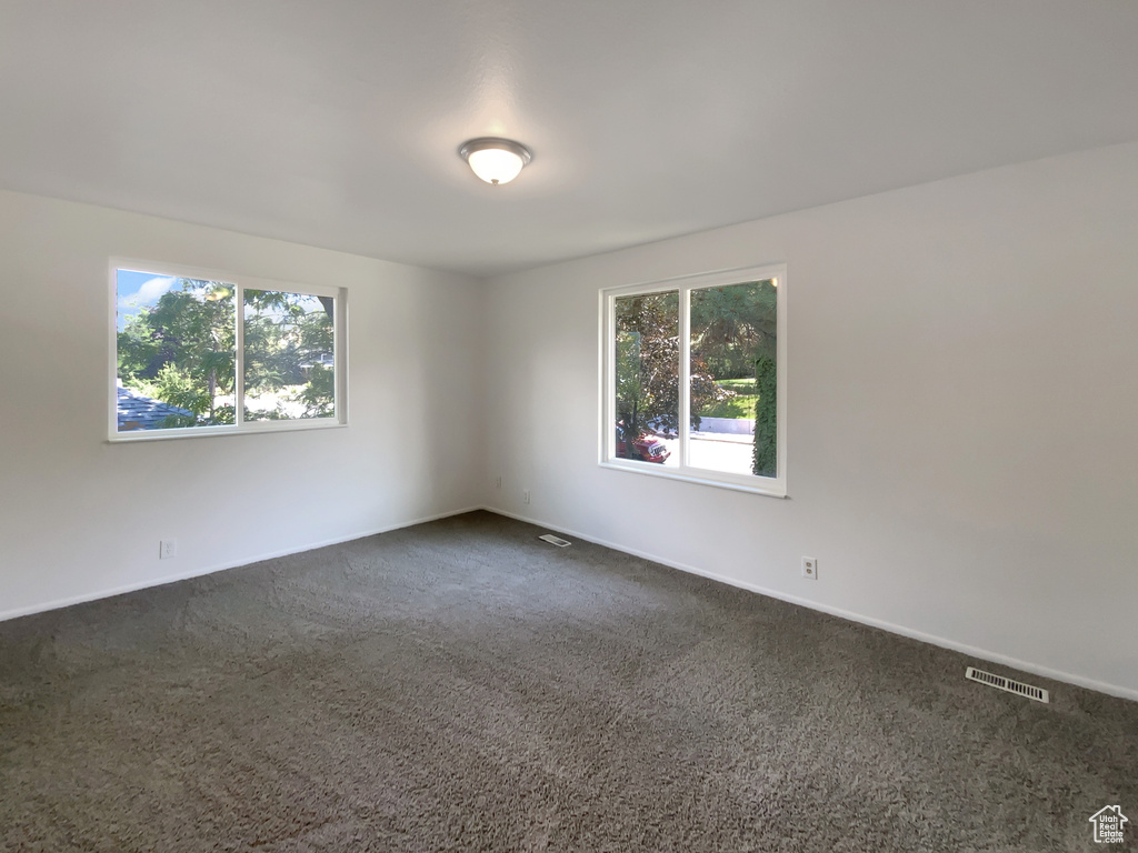 Empty room with plenty of natural light and dark colored carpet