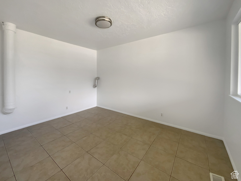Tiled spare room featuring baseboards