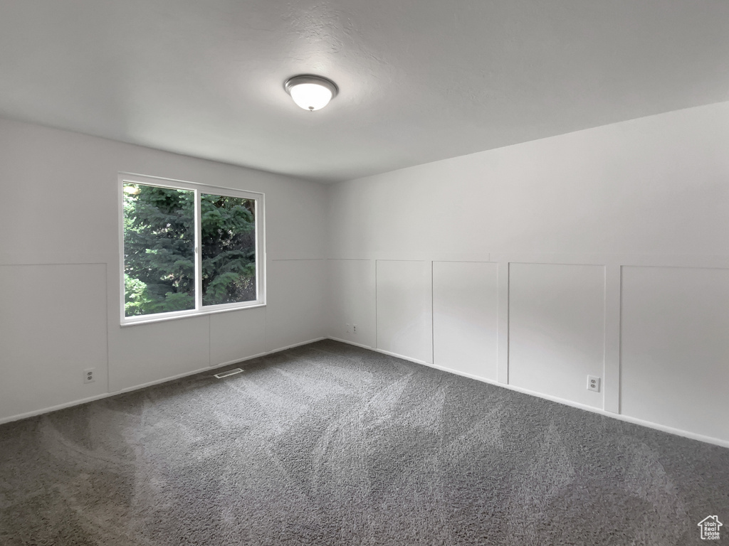 Spare room featuring carpet floors and a decorative wall
