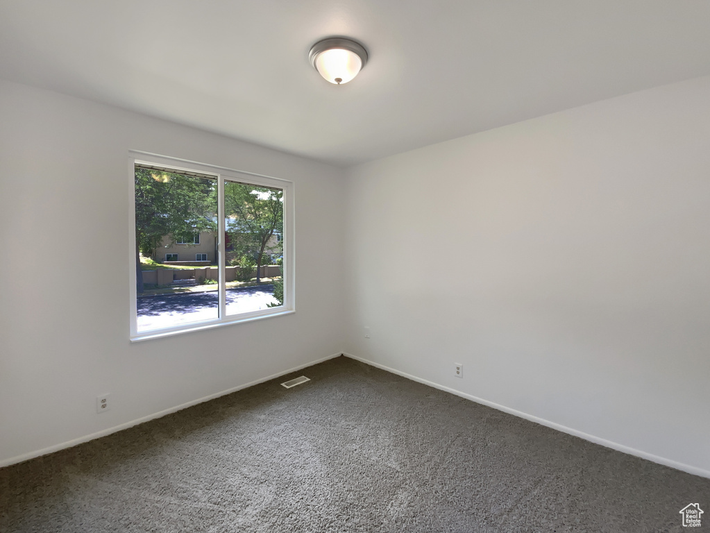 Spare room featuring dark colored carpet and baseboards