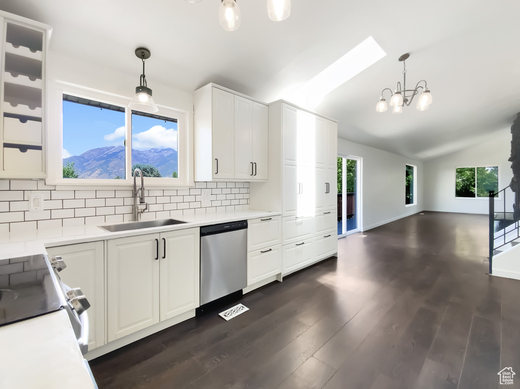 Kitchen with stainless steel appliances, decorative backsplash, vaulted ceiling, a chandelier, and white cabinetry
