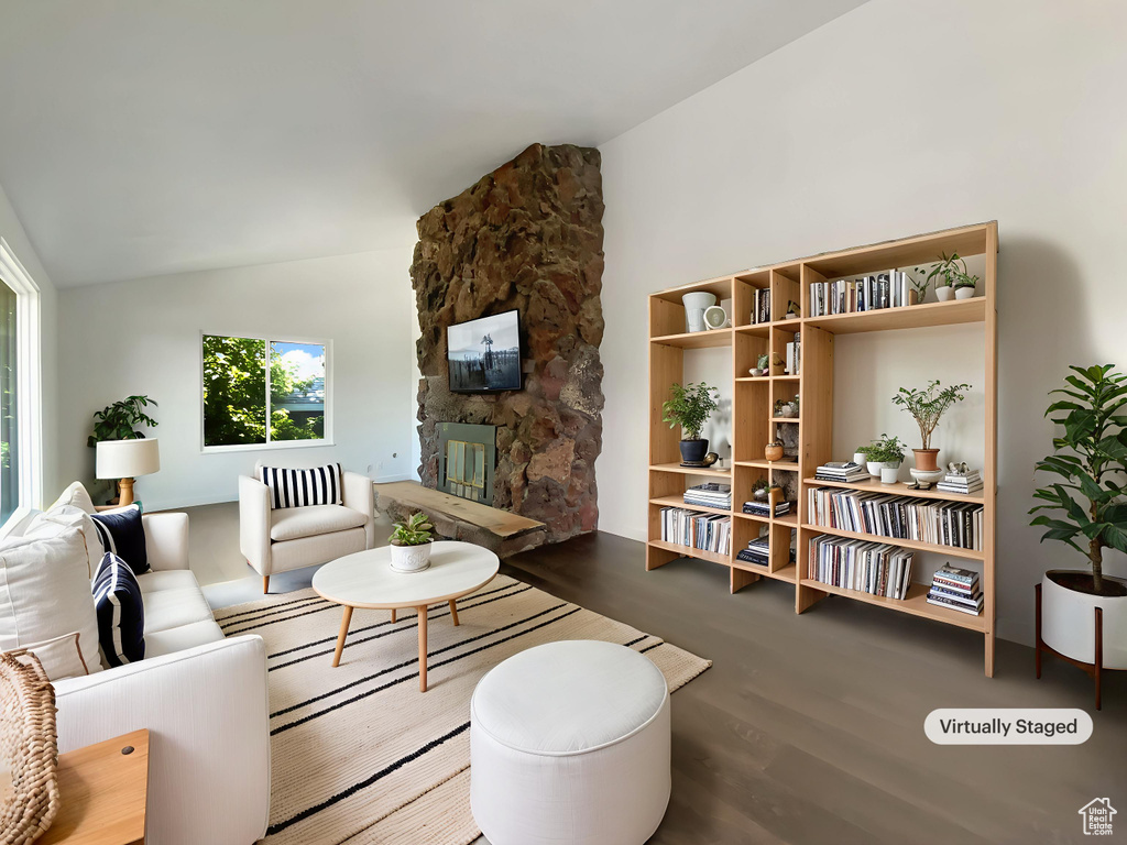 Living area featuring wood finished floors, vaulted ceiling, a fireplace, and healthy amount of natural light