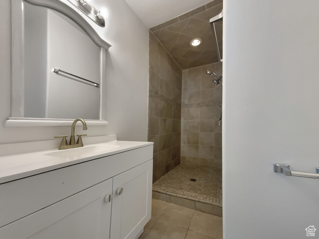 Bathroom featuring a tile shower, vanity, and tile patterned floors