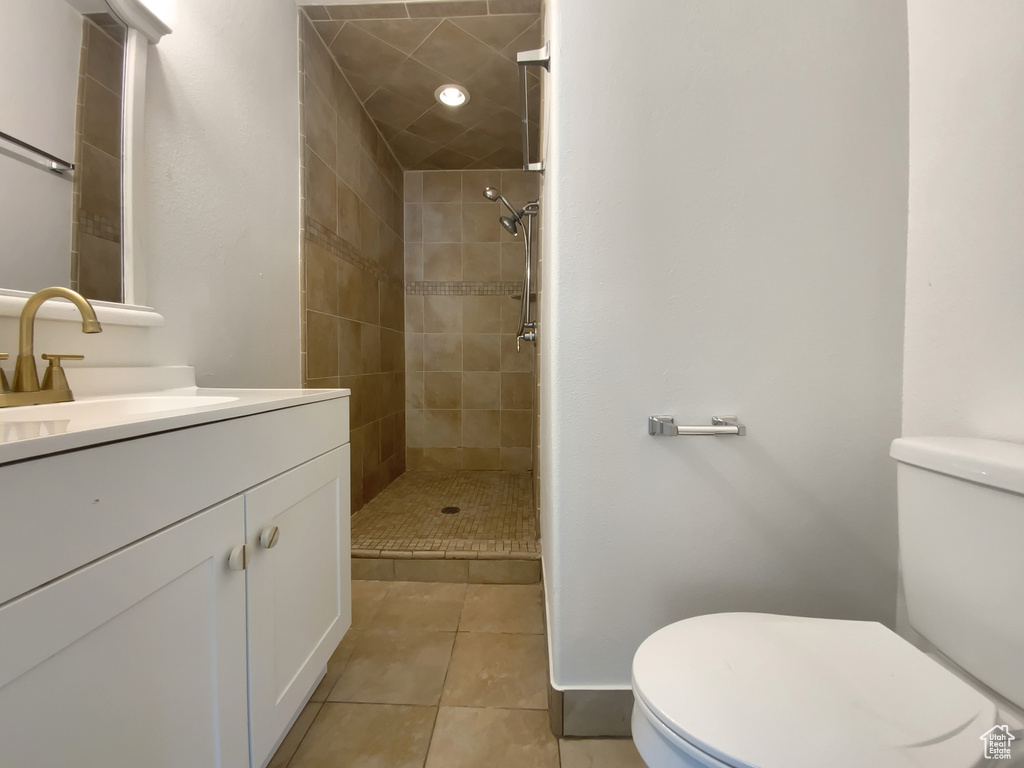 Full bath featuring vanity, tiled shower, and tile patterned floors