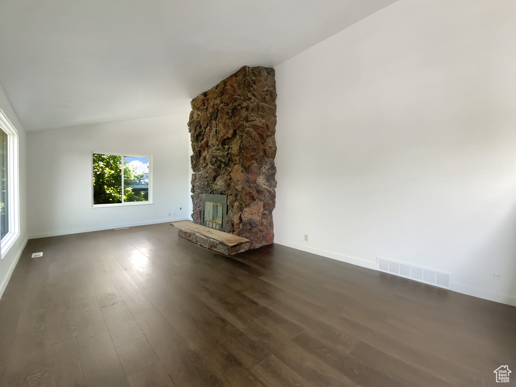 Unfurnished living room with lofted ceiling, dark wood-style flooring, and a fireplace