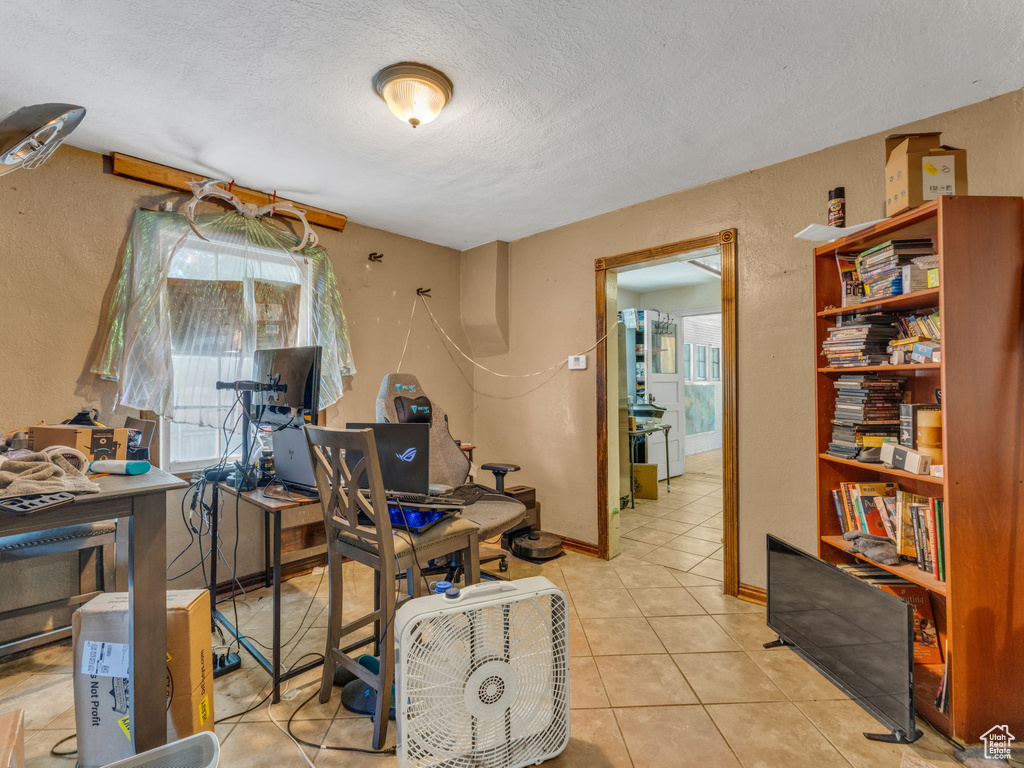 Office space featuring a textured ceiling, tile patterned floors, and a textured wall