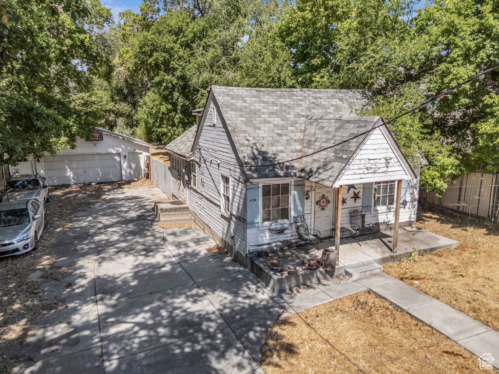View of front facade featuring a shingled roof, an outbuilding, a garage, and concrete driveway