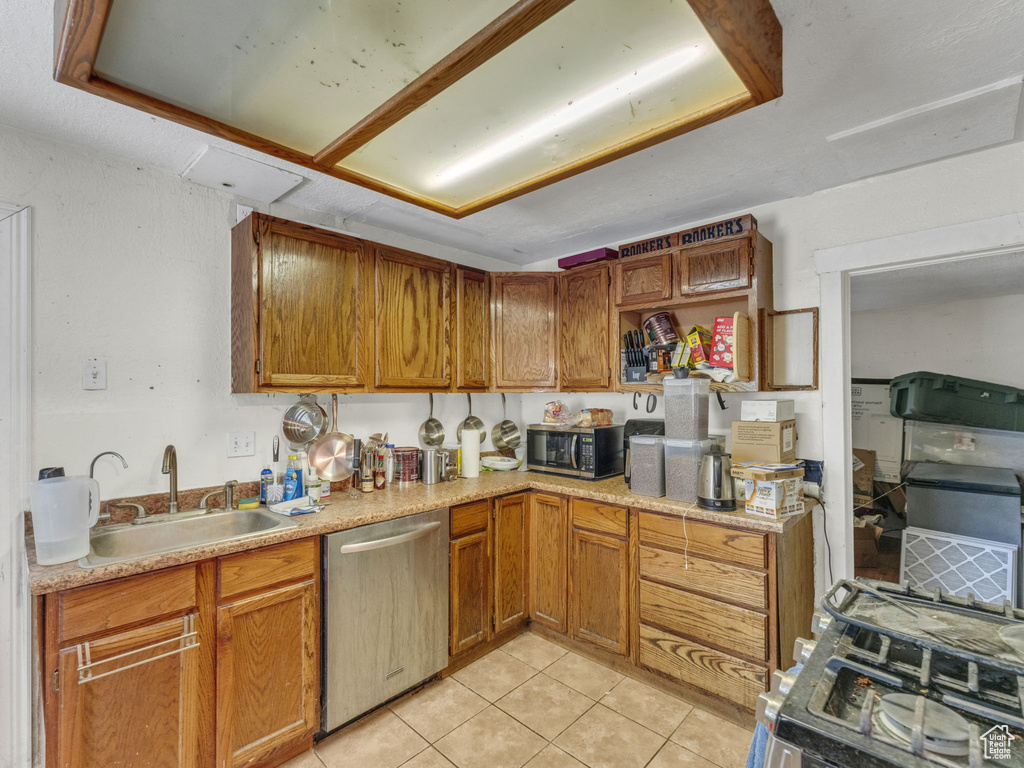 Kitchen featuring appliances with stainless steel finishes, light tile patterned flooring, light countertops, and brown cabinetry