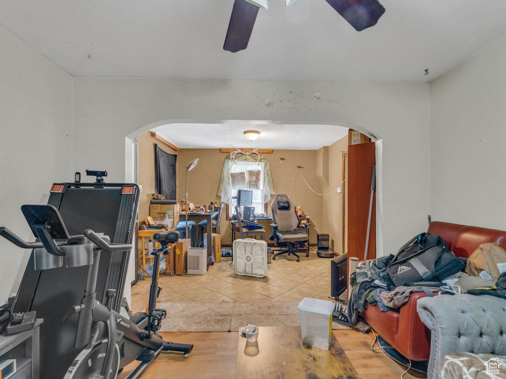 Workout room featuring arched walkways, ceiling fan, and wood finished floors