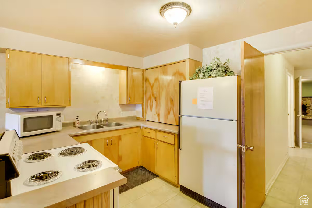 Kitchen featuring white appliances, light countertops, and light brown cabinets