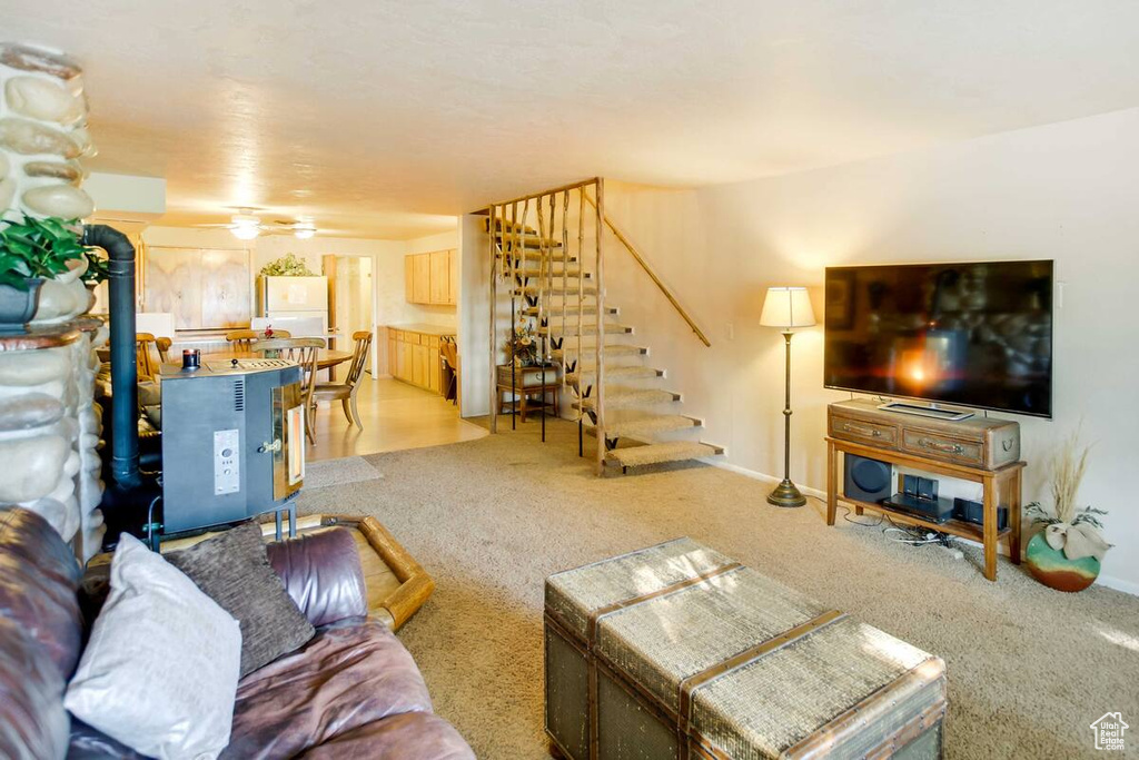 Living room featuring stairs, light colored carpet, and a wood stove