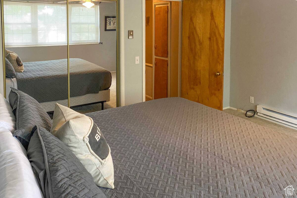 Carpeted bedroom with a baseboard heating unit and a closet