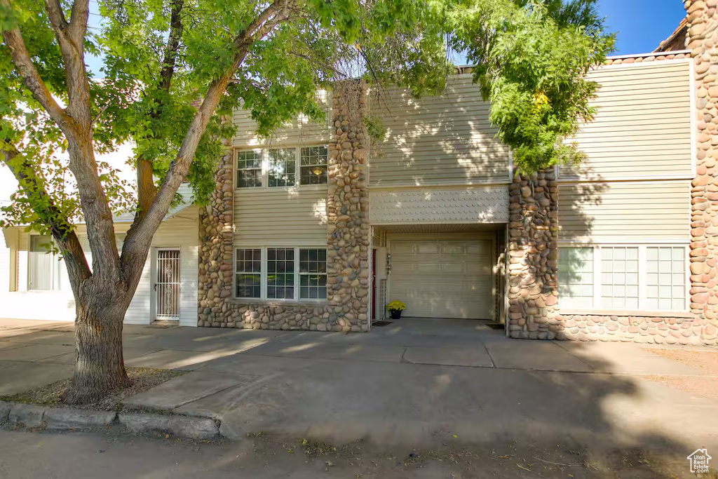 View of front of house featuring stone siding and concrete driveway