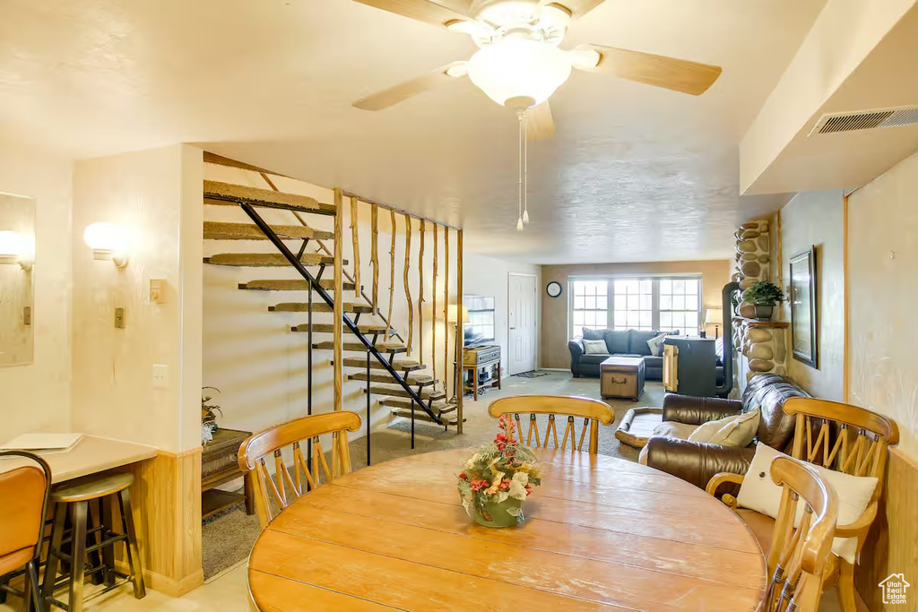 Dining area with stairs, ceiling fan, and carpet
