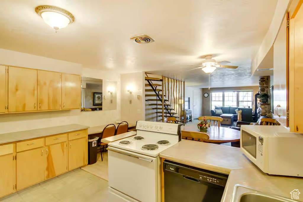 Kitchen featuring white appliances, light countertops, ceiling fan, and open floor plan
