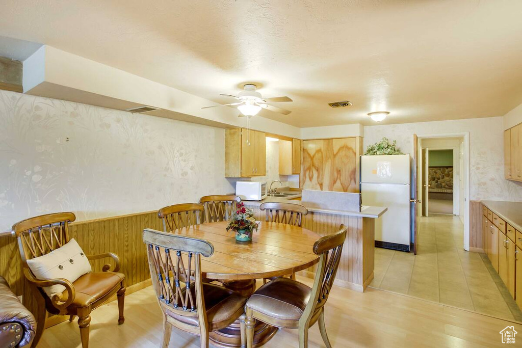 Dining room with ceiling fan, light wood-style flooring, and wallpapered walls