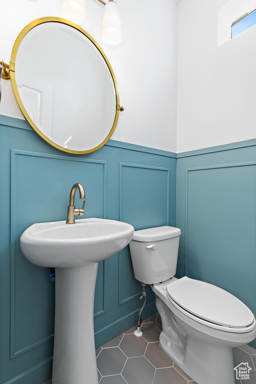Half bathroom with a decorative wall, a wainscoted wall, and tile patterned floors