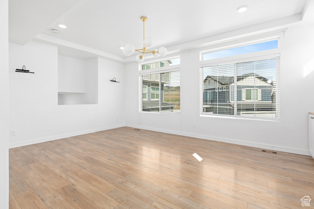 Unfurnished room featuring a chandelier, recessed lighting, light wood-style flooring, a tray ceiling, and a smoke detector