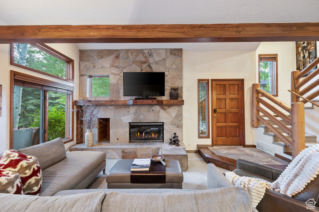 Living room featuring beamed ceiling, a fireplace, and stairway