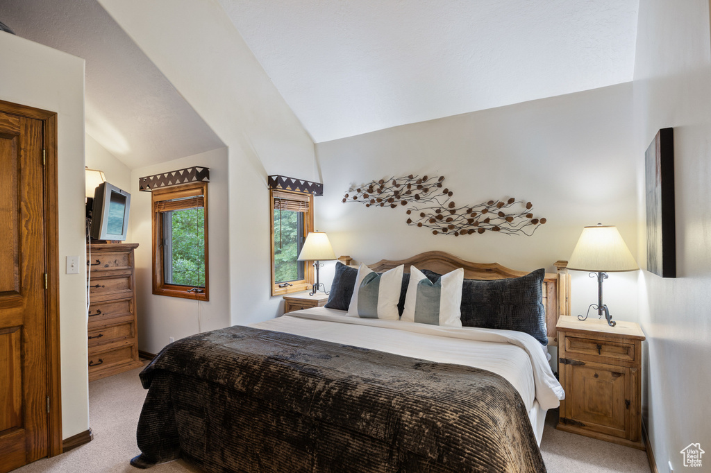 Bedroom featuring light colored carpet and vaulted ceiling
