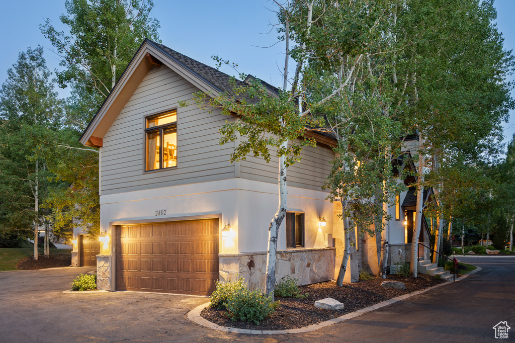 View of front of house featuring stone siding, a garage, and driveway