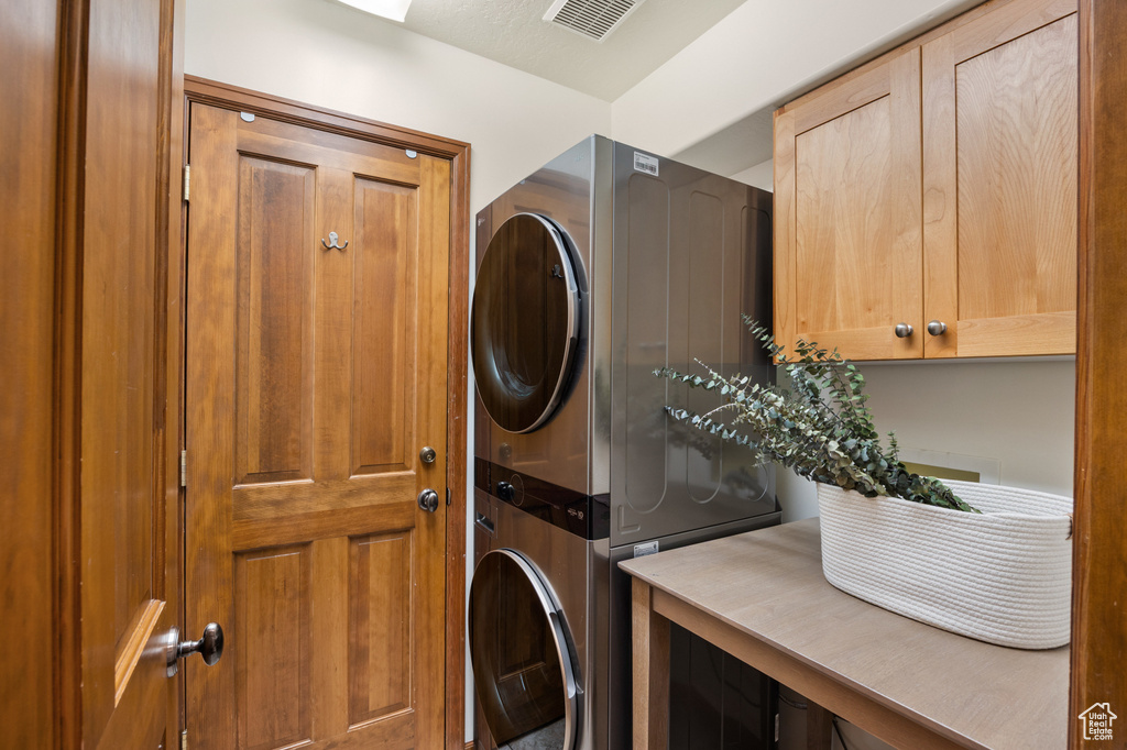 Laundry area with stacked washer / drying machine and cabinet space