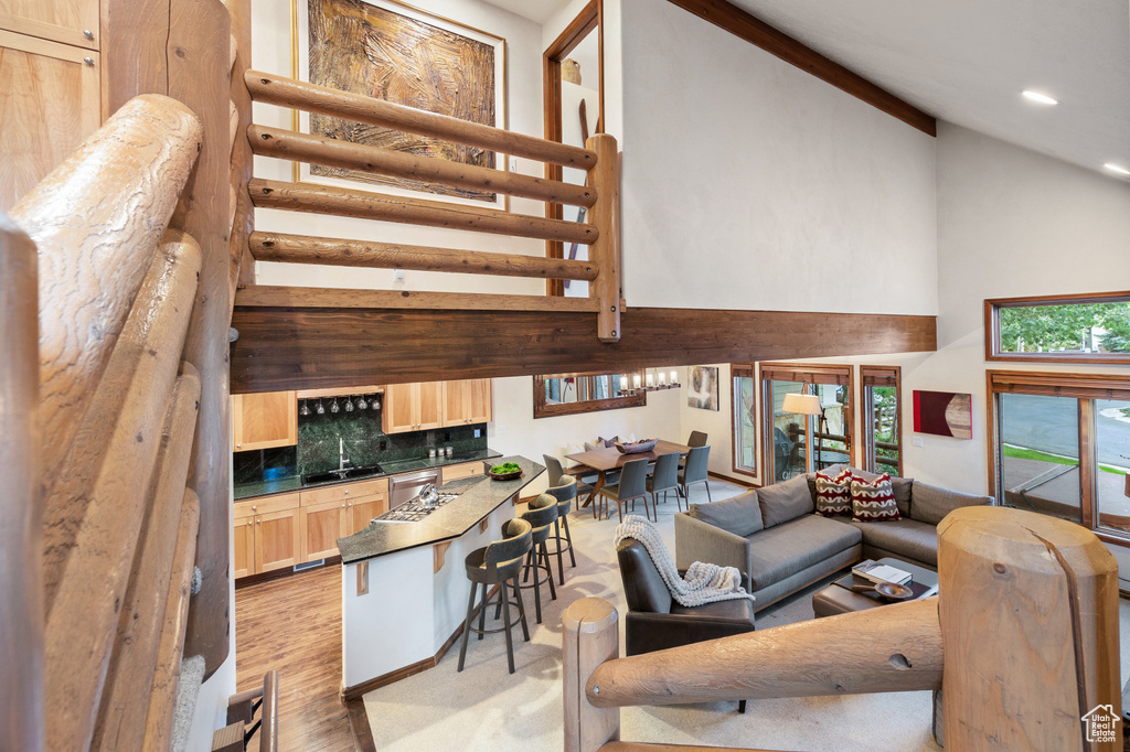Living room with high vaulted ceiling, recessed lighting, light wood-style floors, and stairway